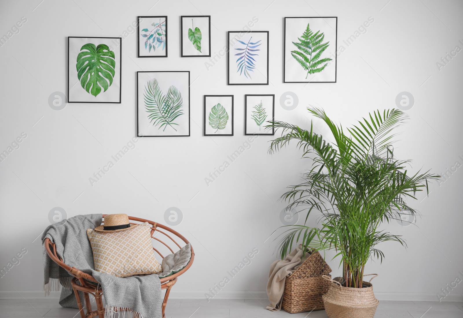 Photo of Beautiful paintings of tropical leaves on white wall in living room interior