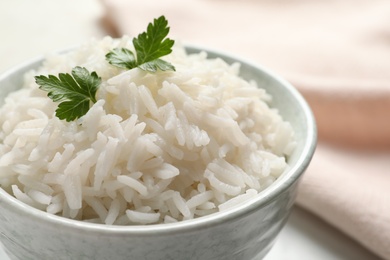 Bowl of tasty cooked rice with parsley on table, closeup