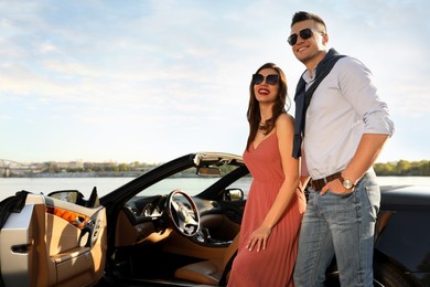 Stylish couple near luxury convertible car outdoors