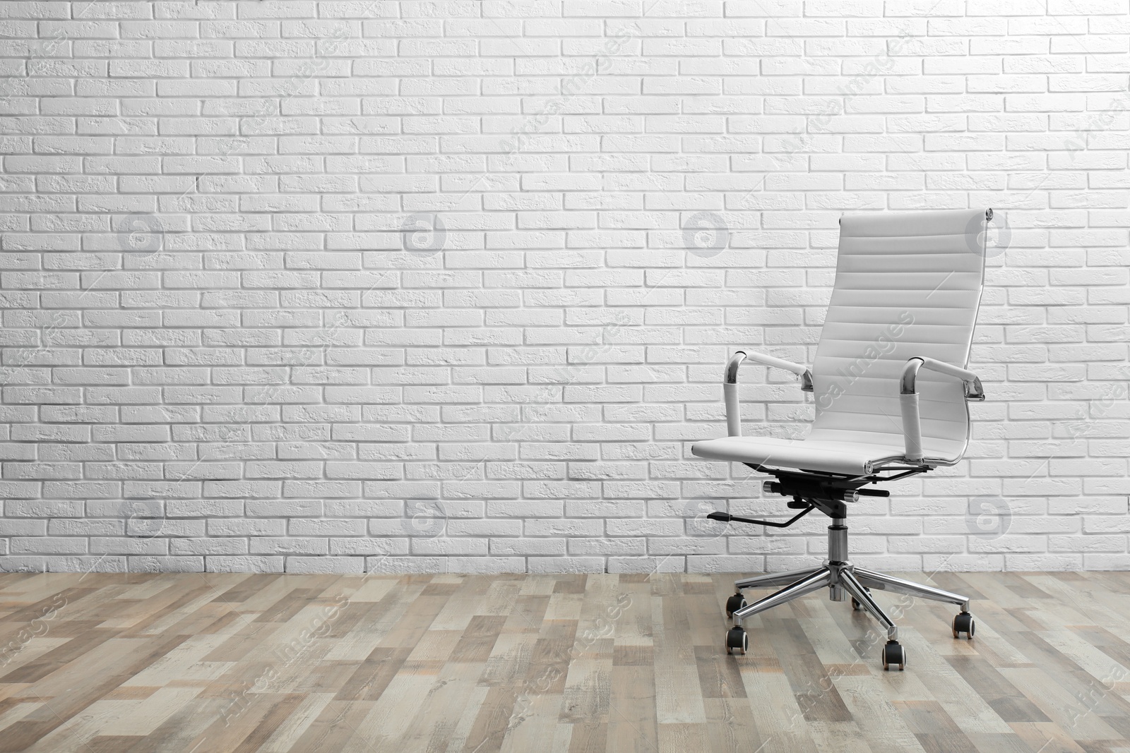 Photo of Comfortable office chair near white brick wall indoors. Space for text