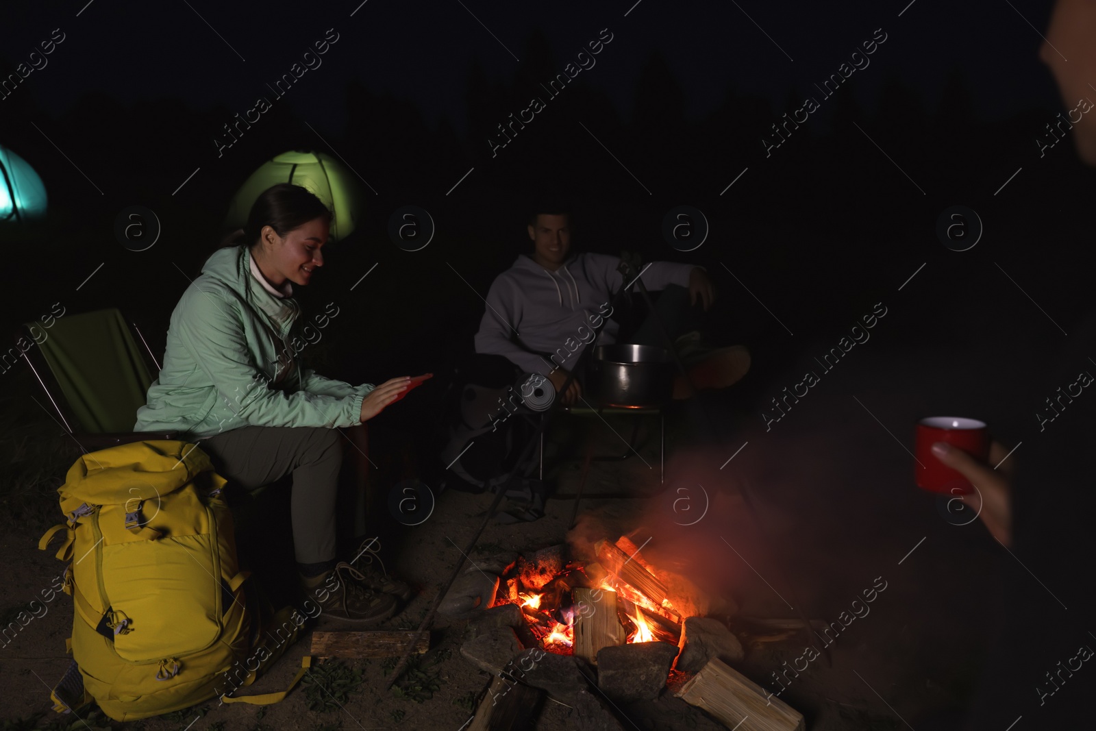 Photo of People sitting near bonfire in camp at night