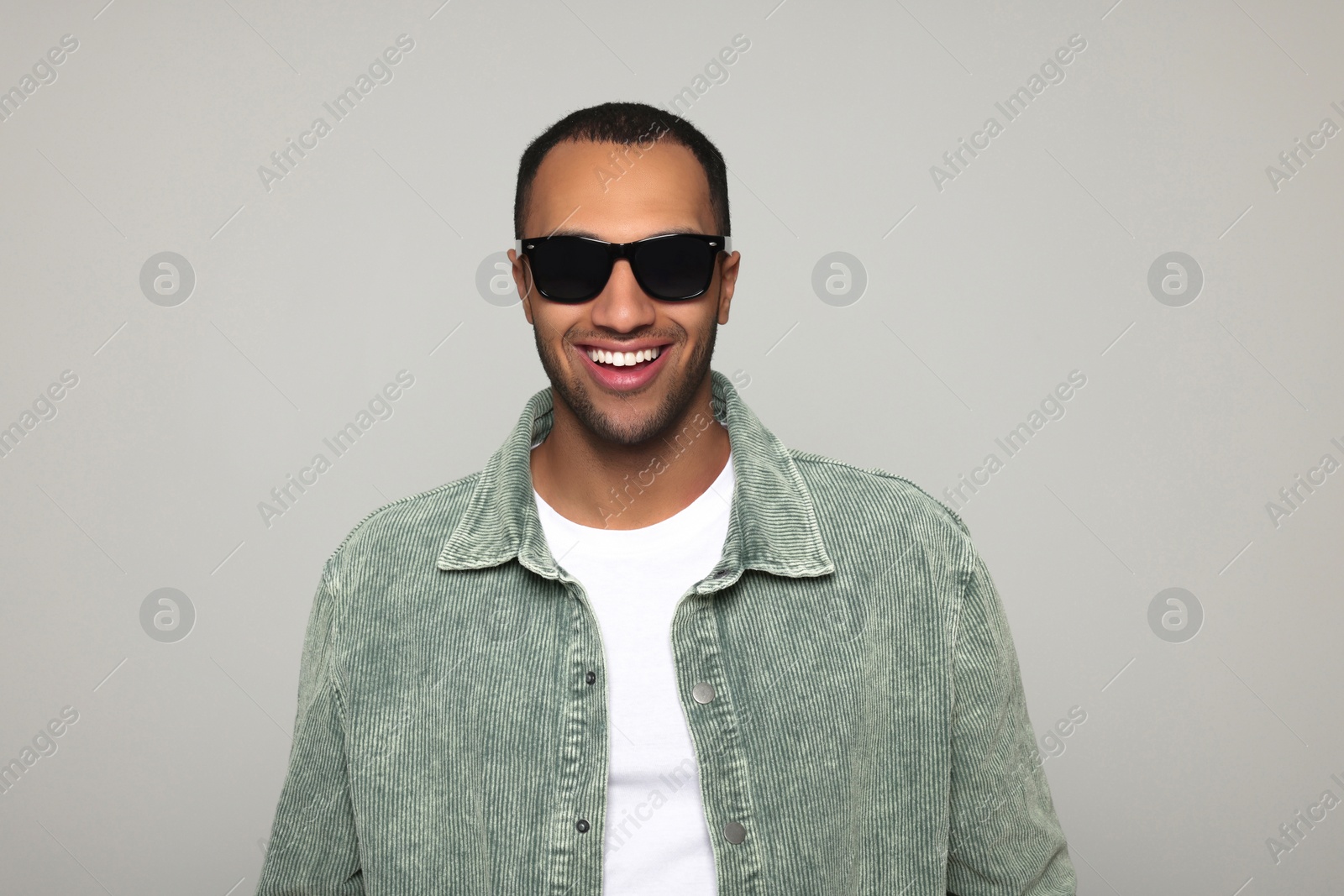 Photo of Portrait of smiling African American man in sunglasses on light grey background