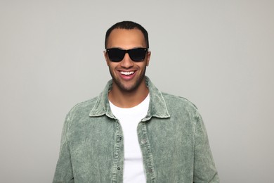 Photo of Portrait of smiling African American man in sunglasses on light grey background