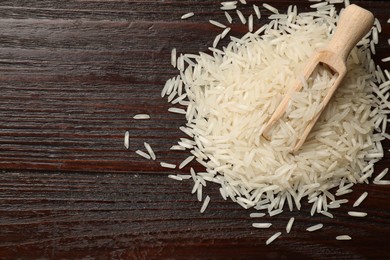 Photo of Raw basmati rice and scoop on wooden table, top view. Space for text