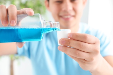 Man pouring mouthwash from bottle into cap, closeup. Teeth care