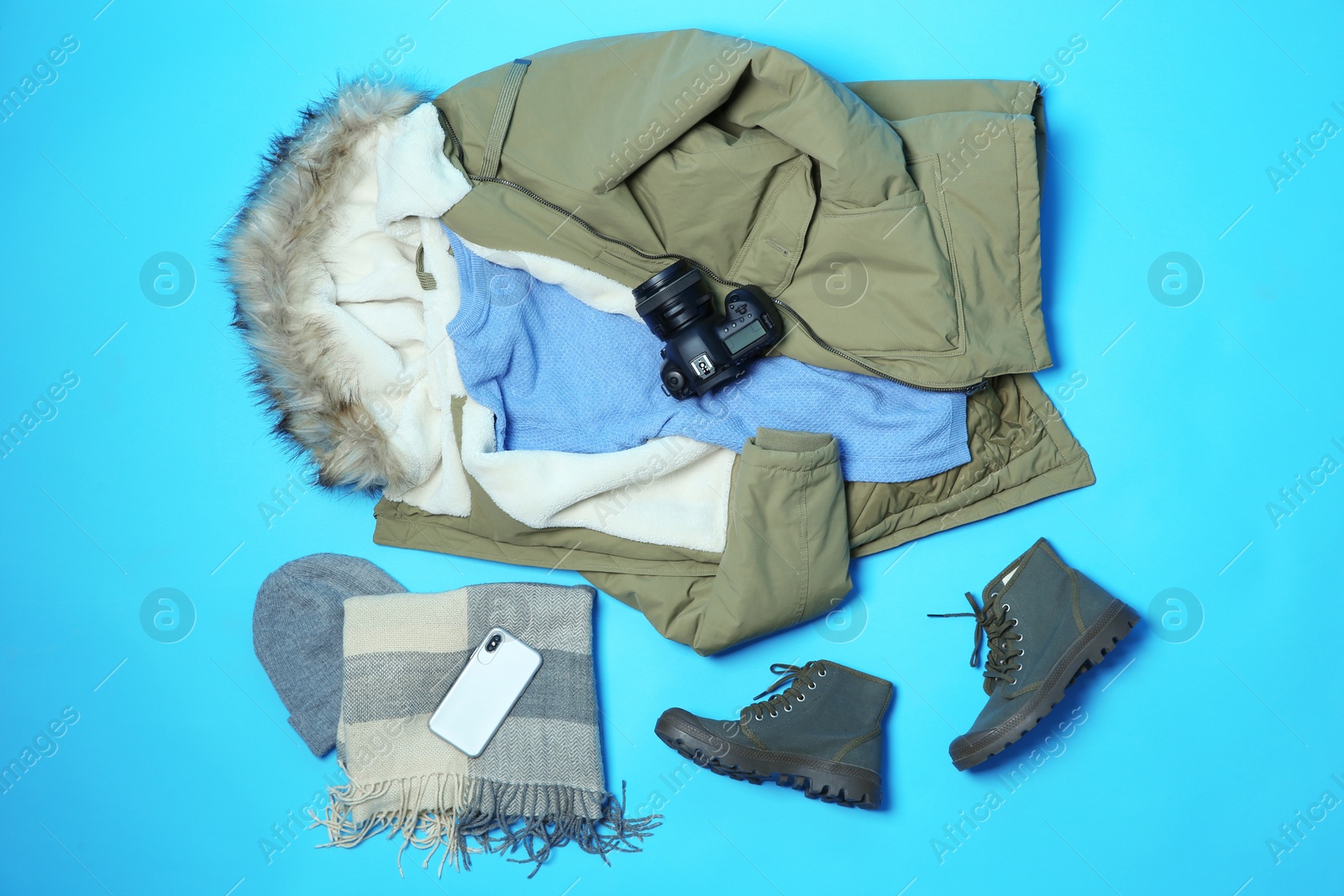 Photo of Flat lay composition with warm clothes for winter vacation on color background