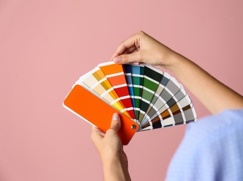 Photo of Female interior designer with palette samples on color background, closeup