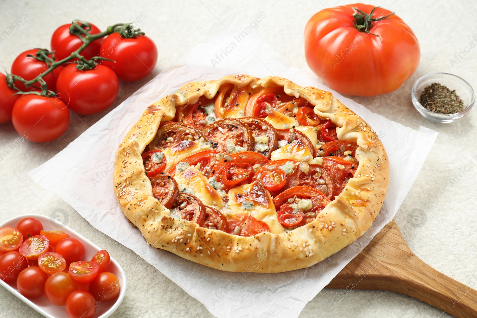 Photo of Tasty galette with tomato and cheese (Caprese galette) on light textured table, closeup