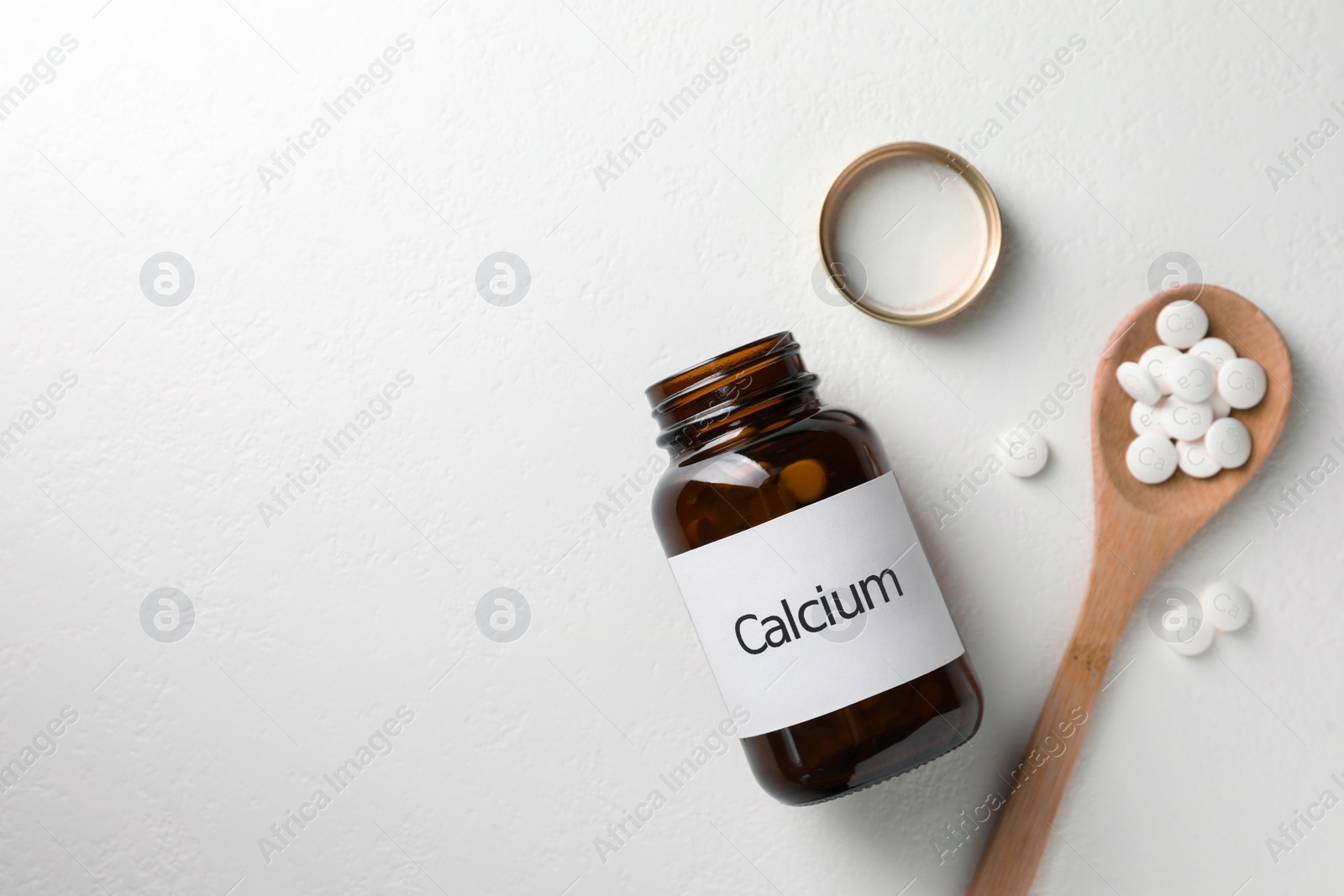 Photo of Calcium supplement pills on white table, flat lay. Space for text