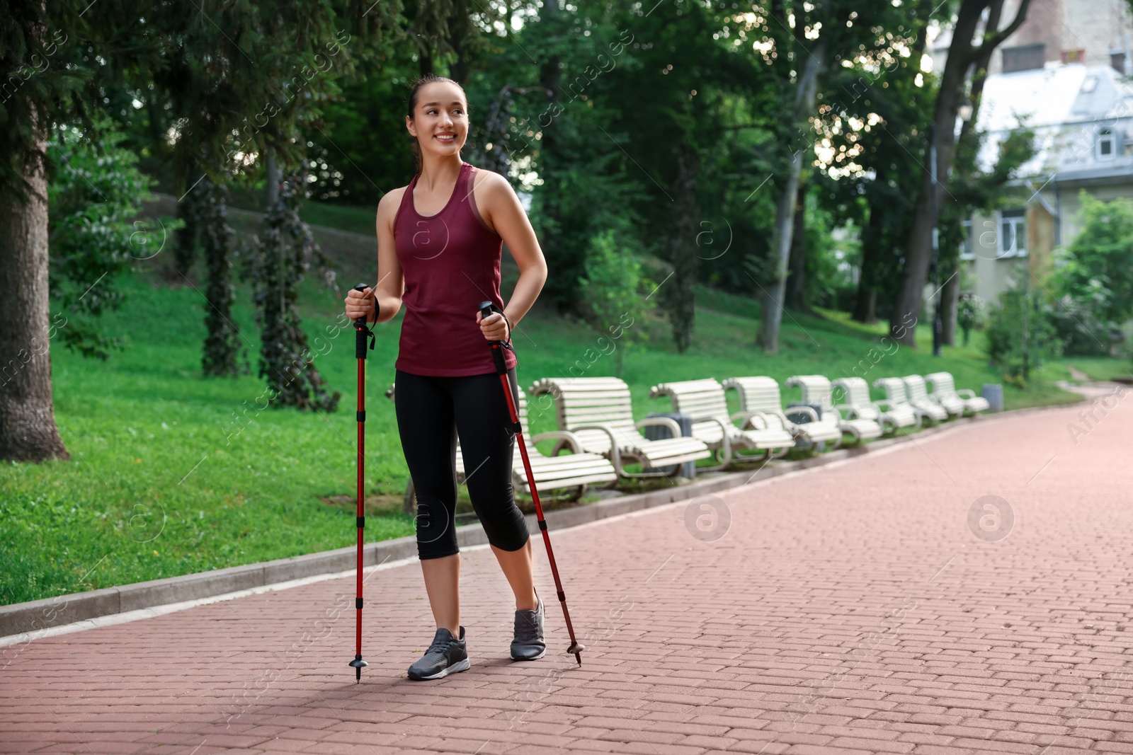 Photo of Young woman practicing Nordic walking with poles outdoors. Space for text