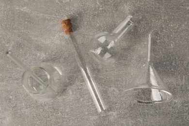 Photo of Different laboratory glassware on grey textured table, flat lay