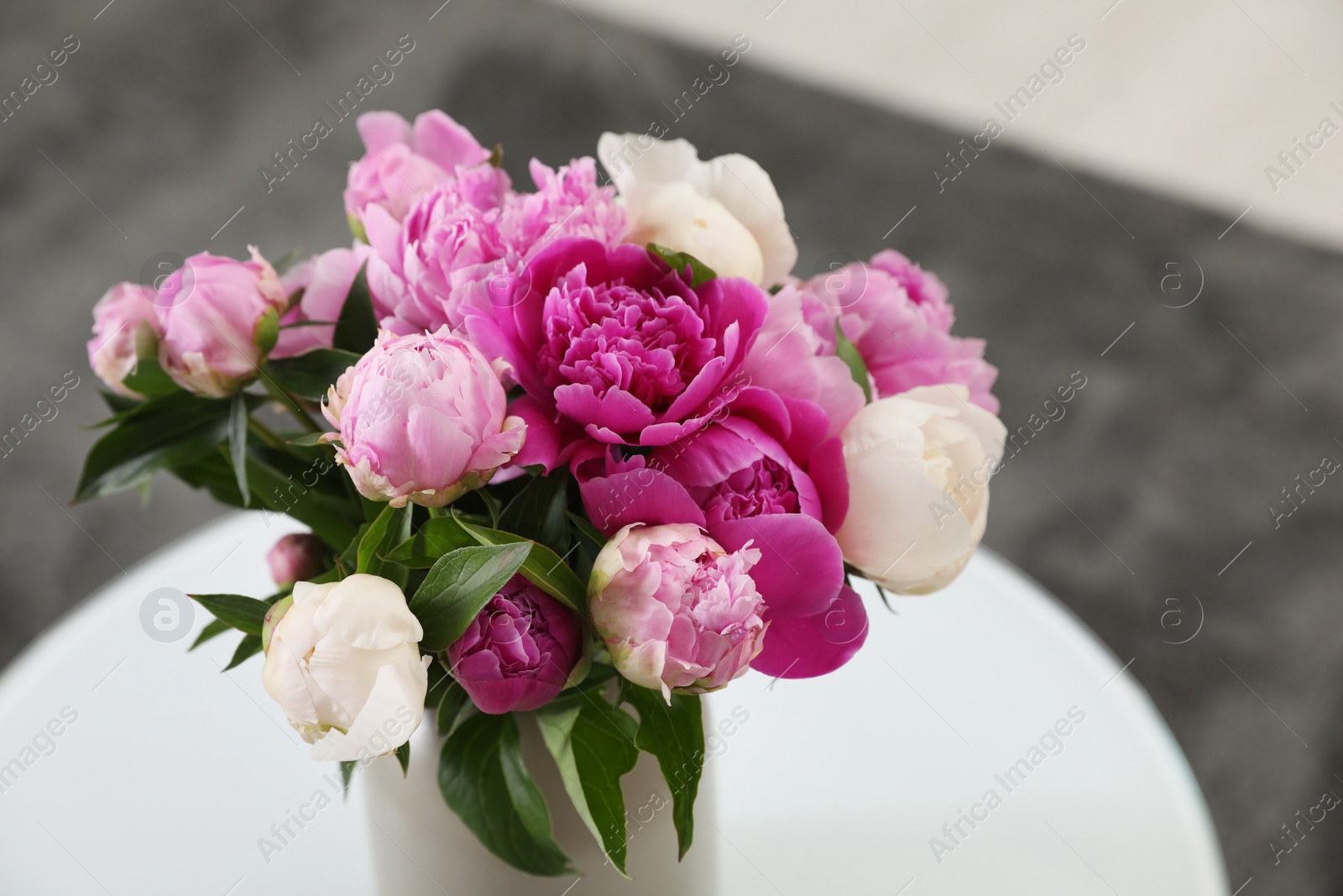 Photo of Vase with bouquet of beautiful peonies on table in room, space for text