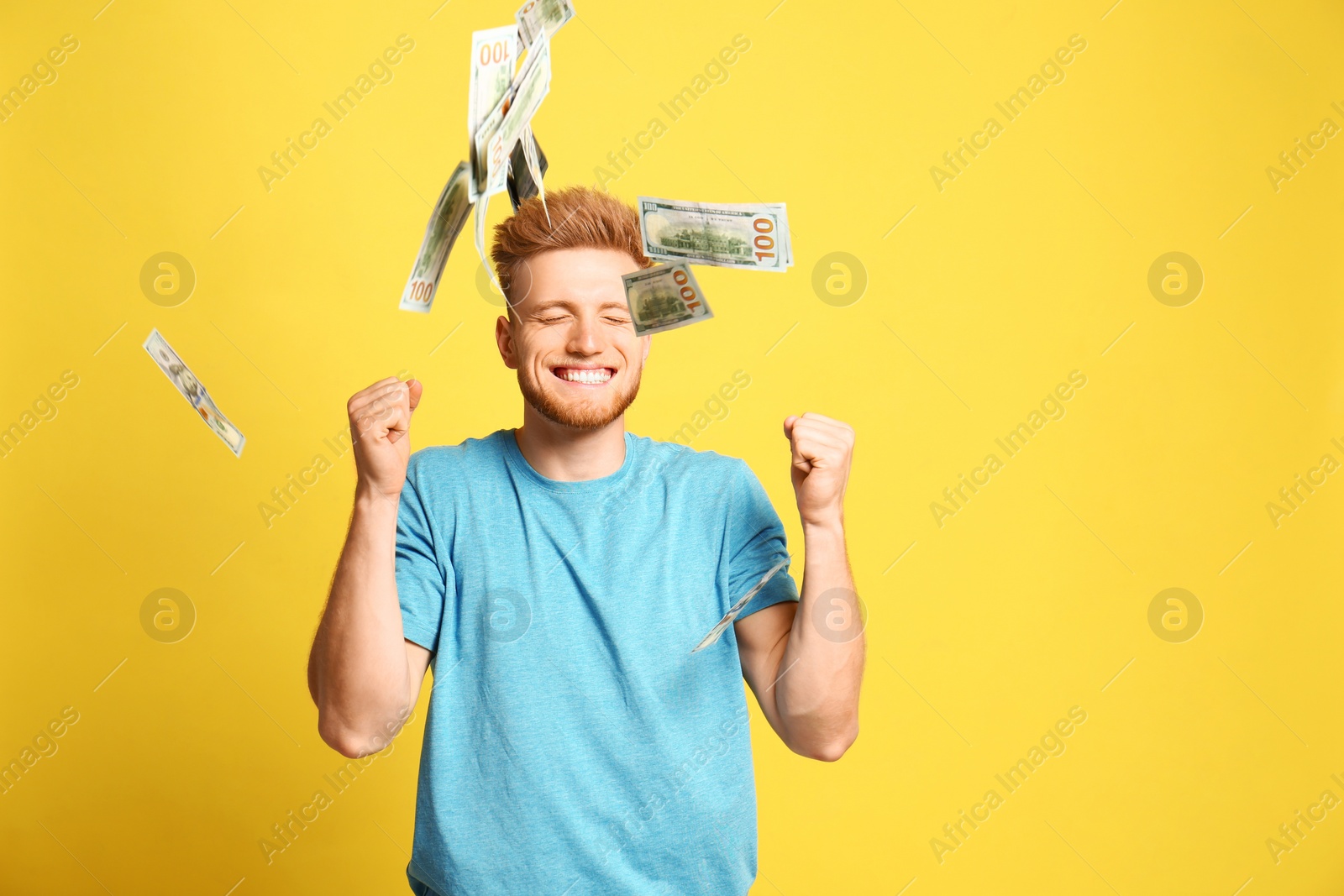 Photo of Portrait of happy lottery winner under money rain on yellow background