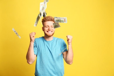 Photo of Portrait of happy lottery winner under money rain on yellow background