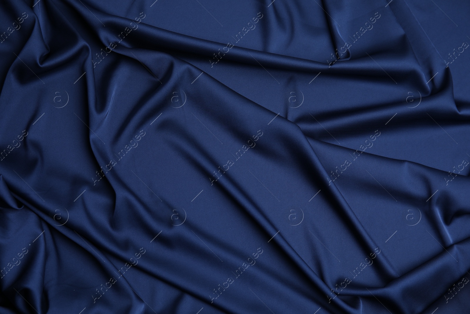 Photo of Crumpled dark blue silk fabric as background, top view