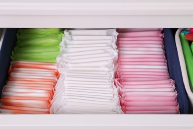 Photo of Open cabinet drawer with different menstrual pads, closeup