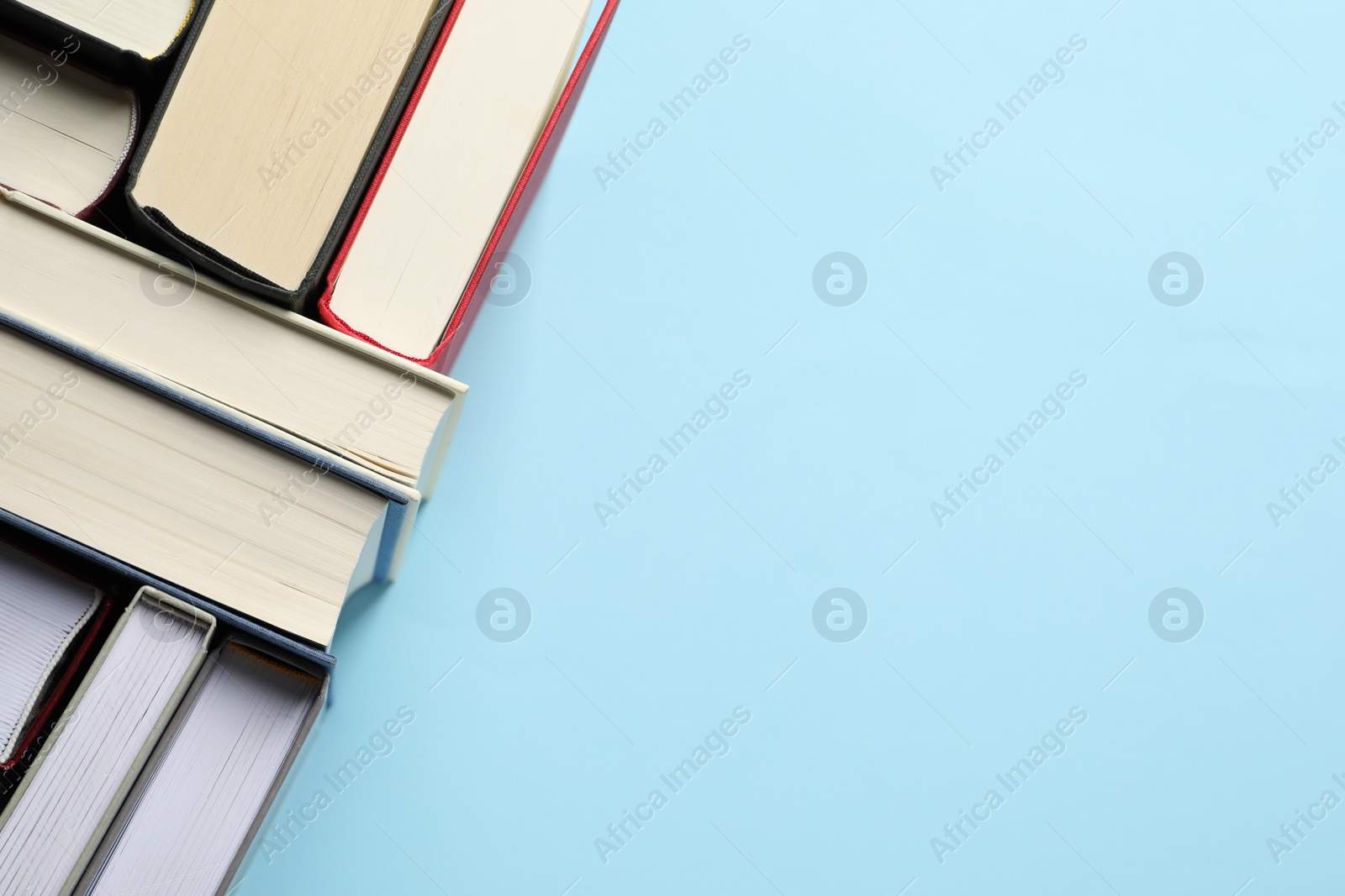 Photo of Many hardcover books on light blue background, top view. Space for text