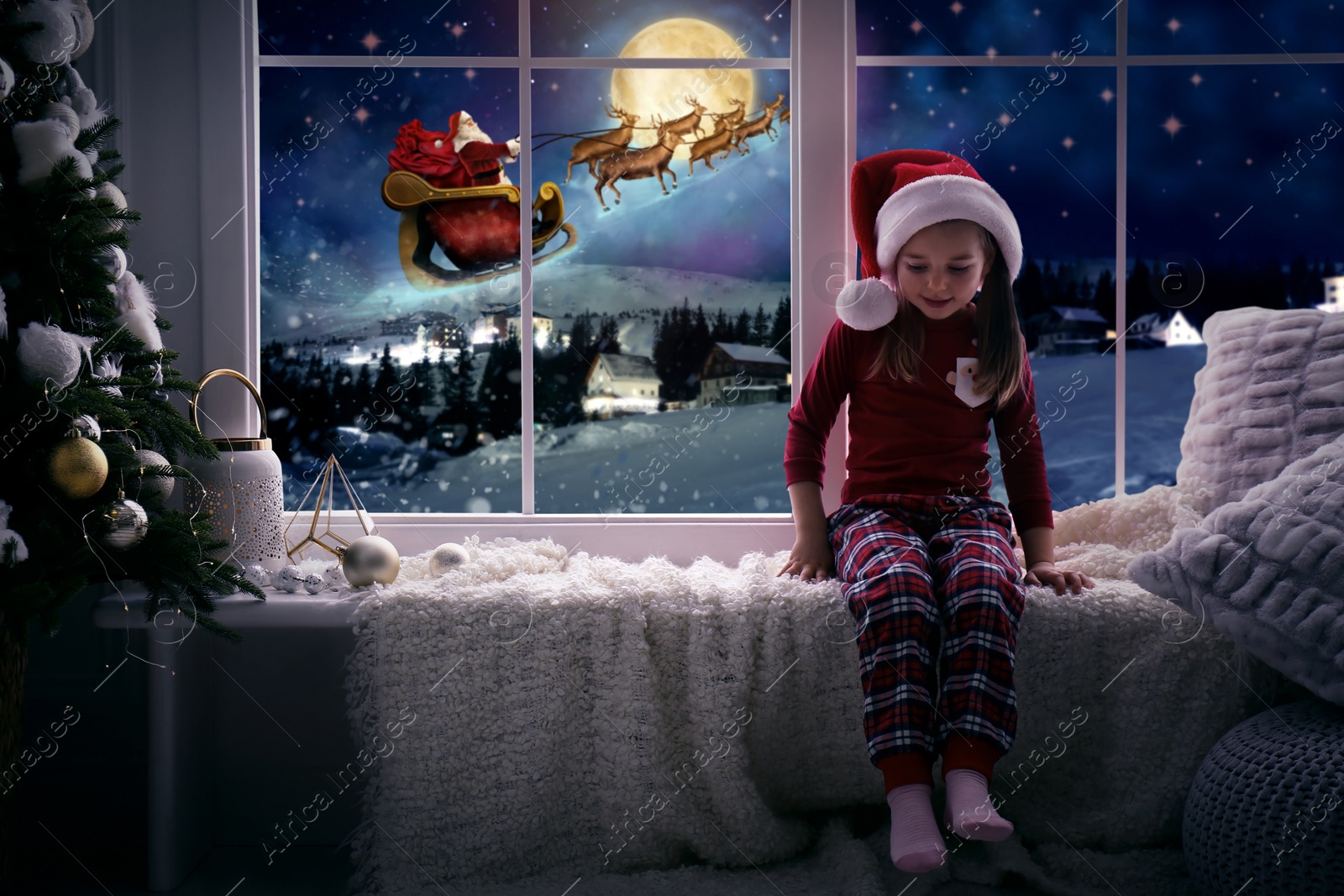 Image of Cute little girl on window sill at home waiting for Santa Claus. Christmas celebration