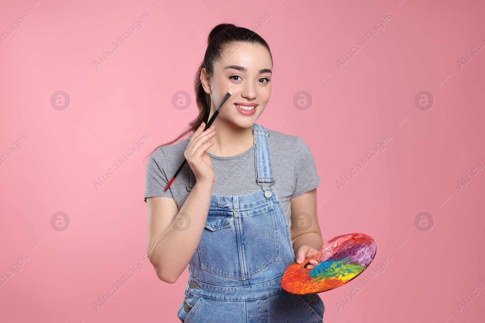 Photo of Woman with painting tools on pink background. Young artist