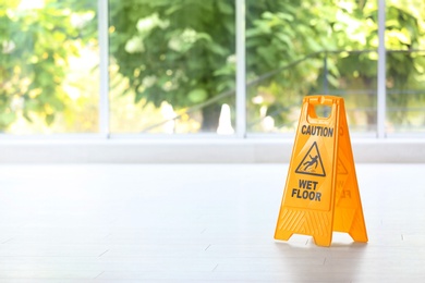 Photo of Safety sign with phrase Caution wet floor, indoors