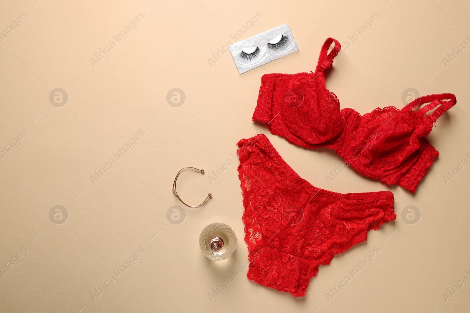 Photo of Elegant red women's underwear, bracelet and perfume on beige background, flat lay. Space for text