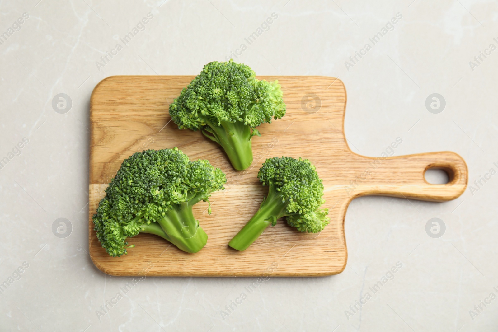 Photo of Fresh green broccoli on light marble table, top view