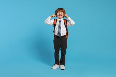 Photo of Happy schoolboy with backpack on light blue background