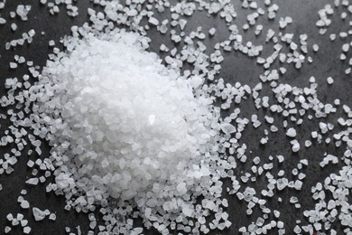 Photo of Heap of natural salt on black table, top view