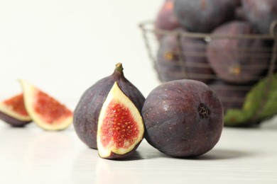 Photo of Whole and cut tasty fresh figs on white table, closeup