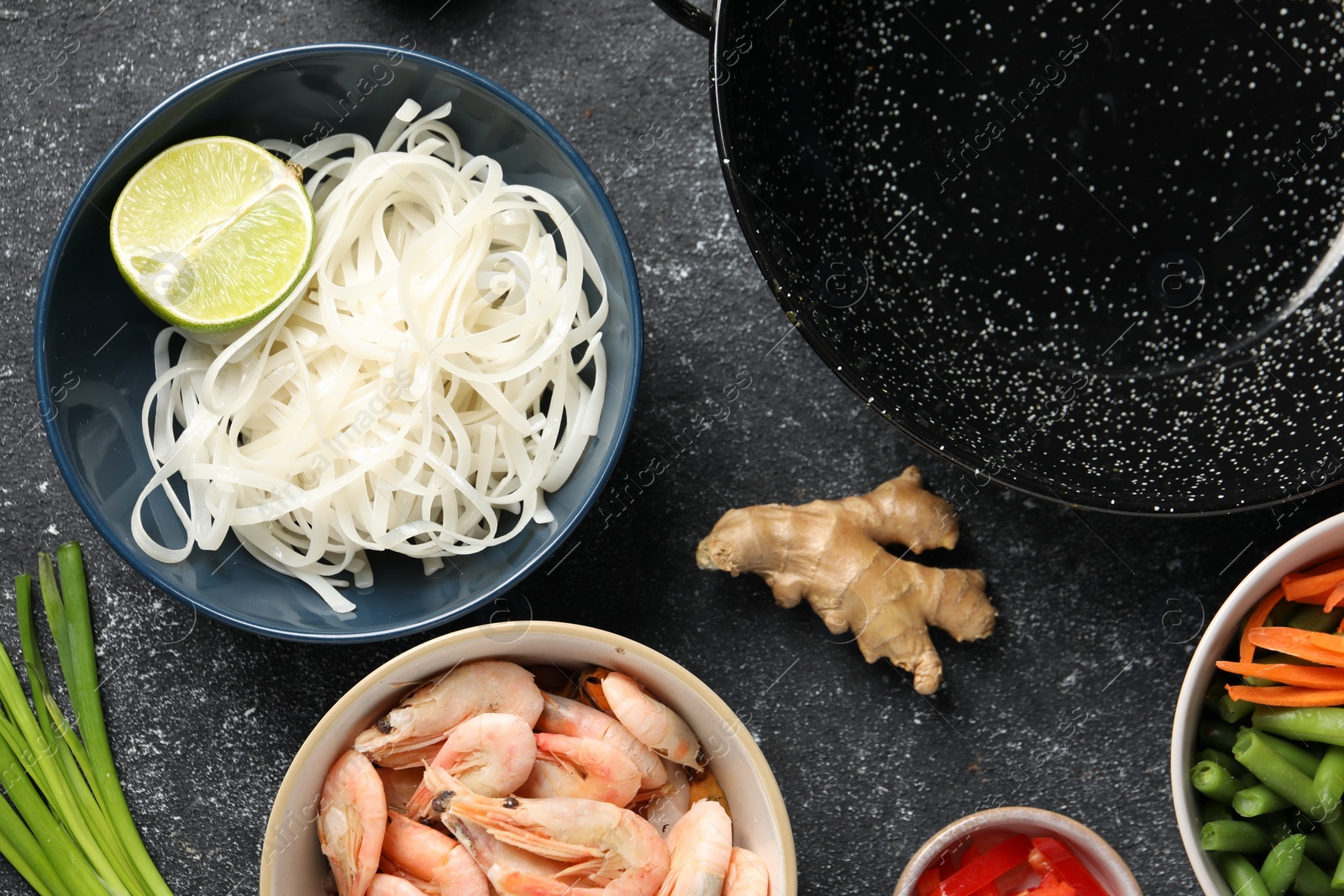 Photo of Flat lay composition with black wok and products on dark textured table