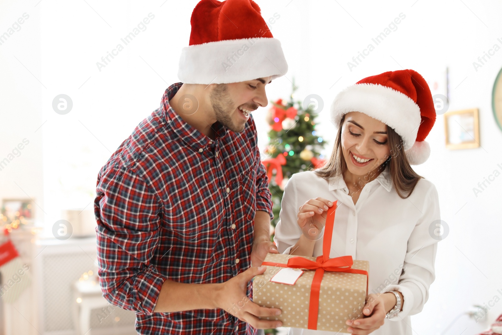 Photo of Young couple with Christmas gift at home