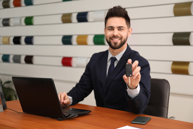 Salesman with car key at desk in office