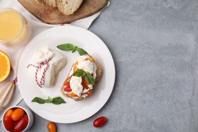 Delicious sandwich with burrata cheese and tomatoes served on grey table, flat lay. Space for text