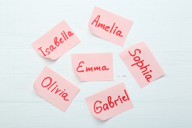 Paper stickers with different names on white wooden background, flat lay. Choosing baby's name