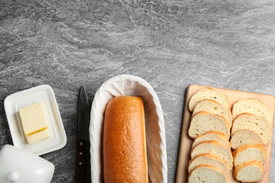 Tasty fresh bread with butter on grey table, flat lay. Space for text