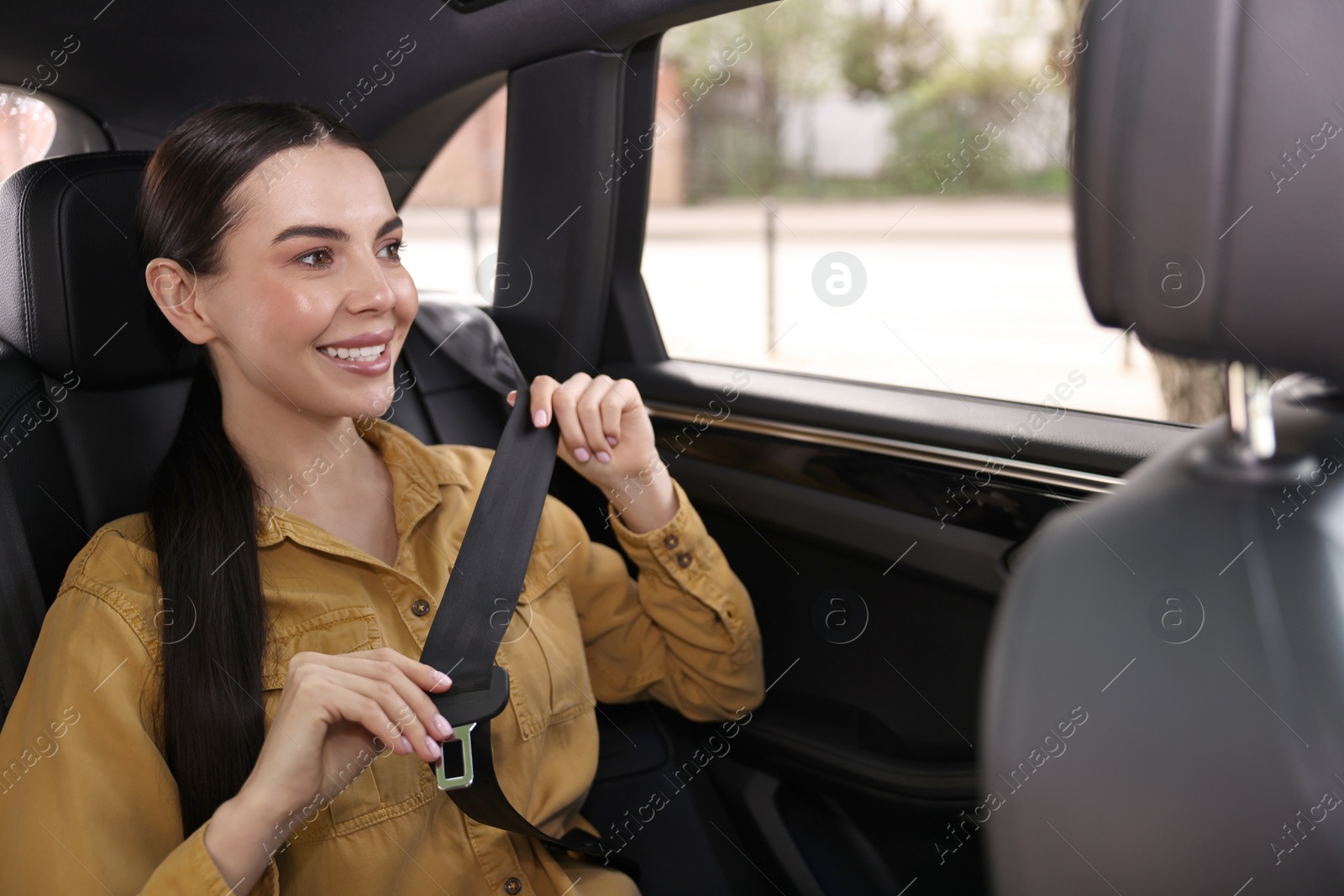 Photo of Woman fastening safety seat belt inside modern car