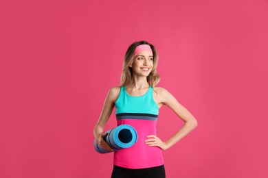 Beautiful woman with yoga mat on pink background