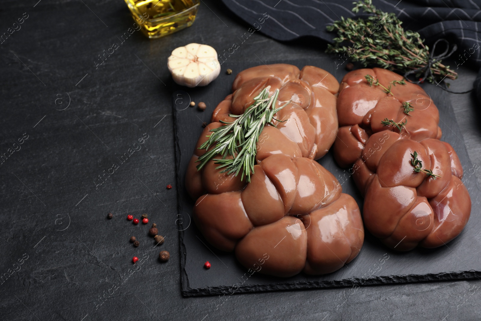 Photo of Fresh raw kidneys with seasonings on black table, space for text