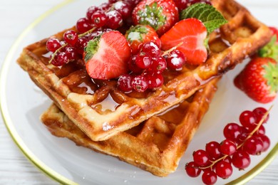 Delicious Belgian waffles with berries and honey on plate, closeup