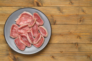 Raw beef tongue pieces on wooden table, top view and space for text