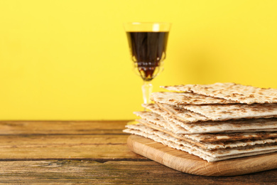 Passover matzos and glass of wine on wooden table, space for text. Pesach celebration