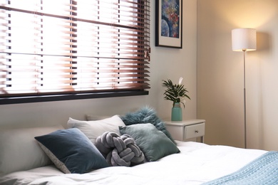 Modern room interior with comfortable double bed and window blinds