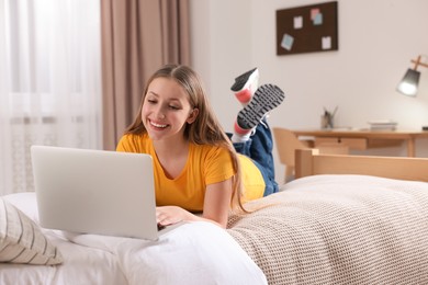 Online learning. Teenage girl with laptop on bed at home