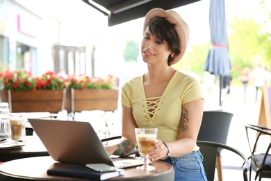 Young woman working with laptop at desk in cafe