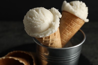 Photo of Ice cream scoops in wafer cones on gray table, closeup