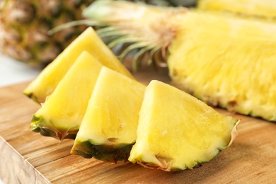 Photo of Cut fresh juicy pineapple on wooden board, closeup