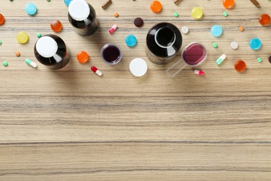 Flat lay composition with cough drops, syrup and pills on wooden background. Space for text