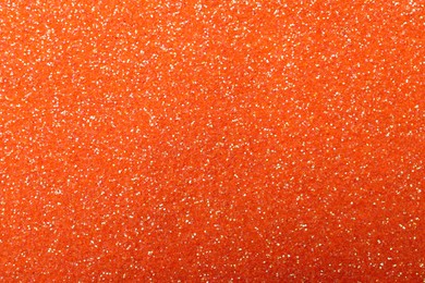 Photo of Beautiful shiny orange glitter as background, closeup