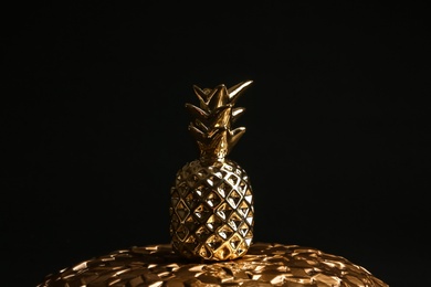 Photo of Gold decorative pineapple on plate against black background
