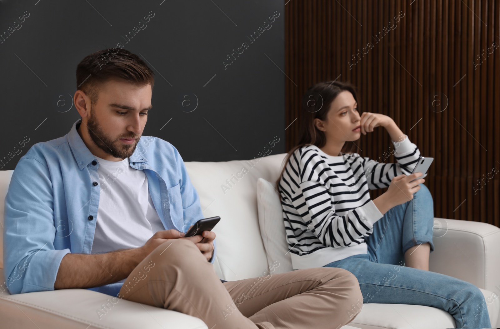 Photo of Couple addicted to smartphones ignoring each other at home. Relationship problems